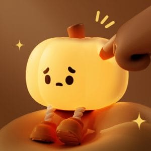 Glowing pumpkin night light with dangling legs on bedside table